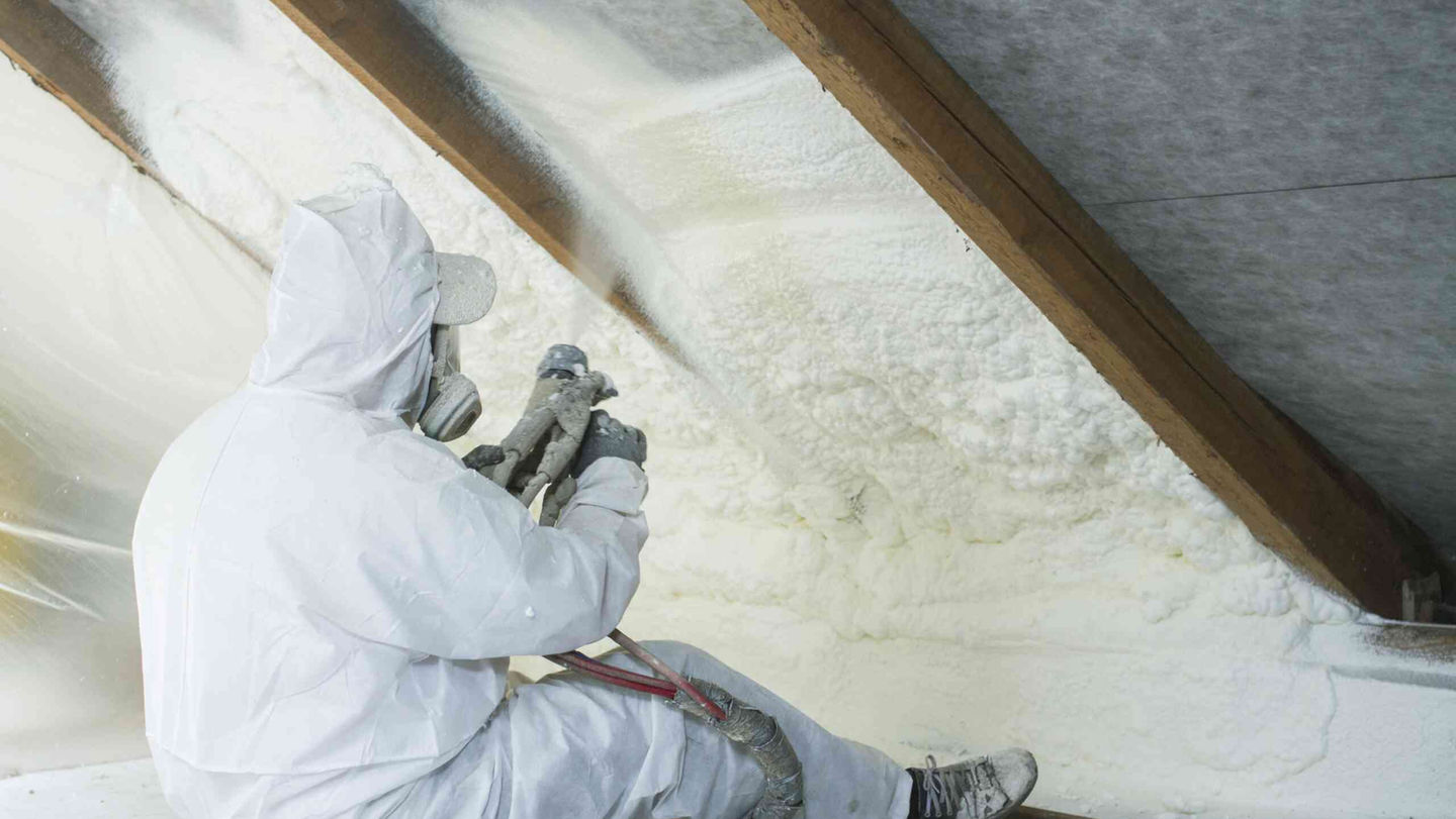 Worker installing spray foam insulation in attic