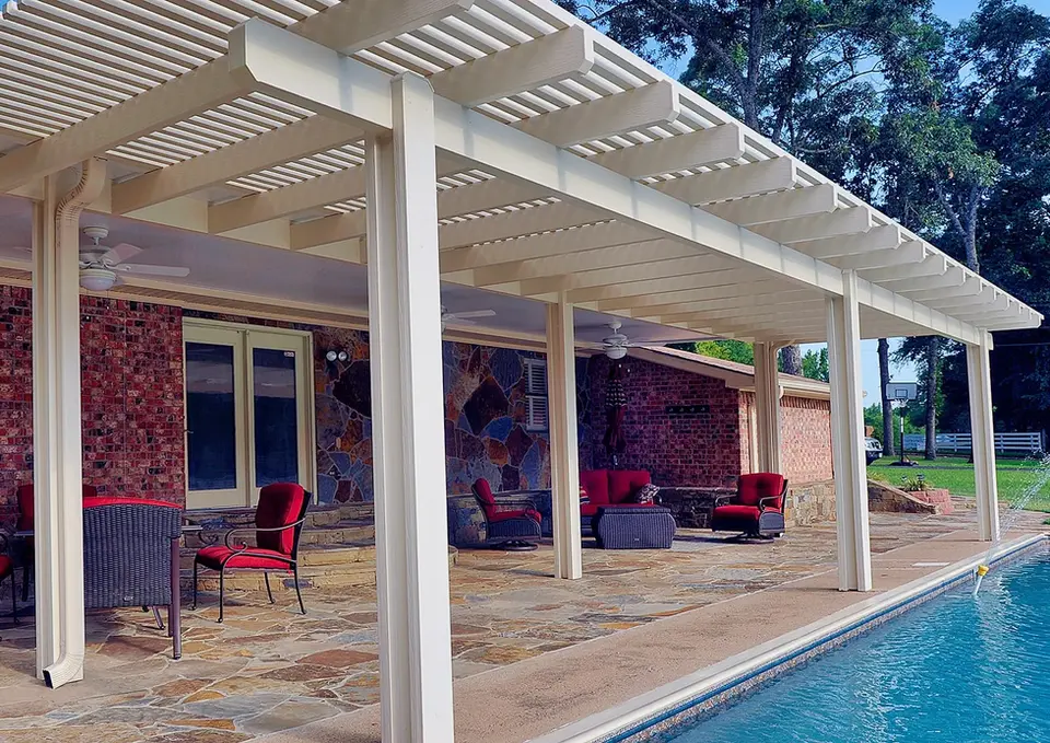 White pergola covers patio furniture near pool