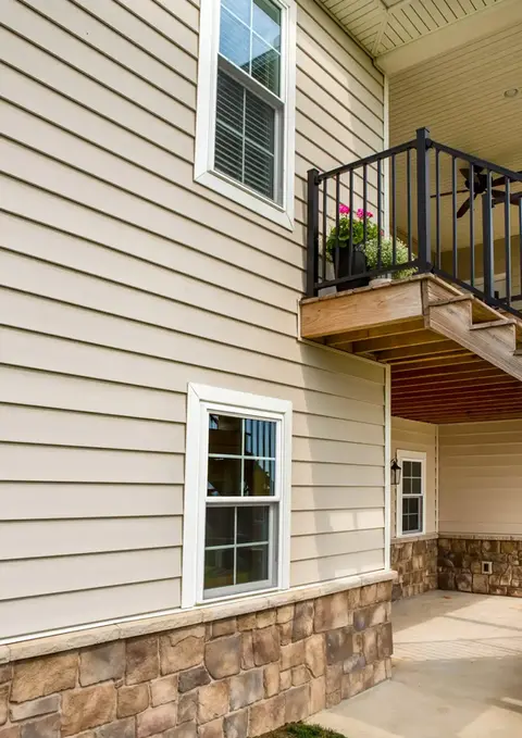Tan house exterior with balcony, windows, and stone accents