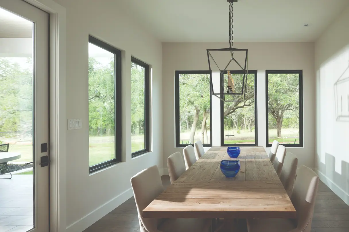 Bright dining room with large windows, wooden table, and modern chandelier