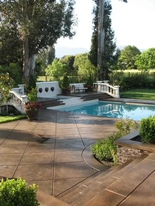 Stamped concrete pool deck with steps, surrounded by landscaping