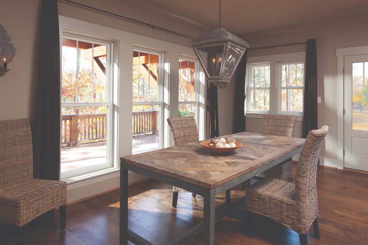 Sunlit dining room with large windows and wooden table