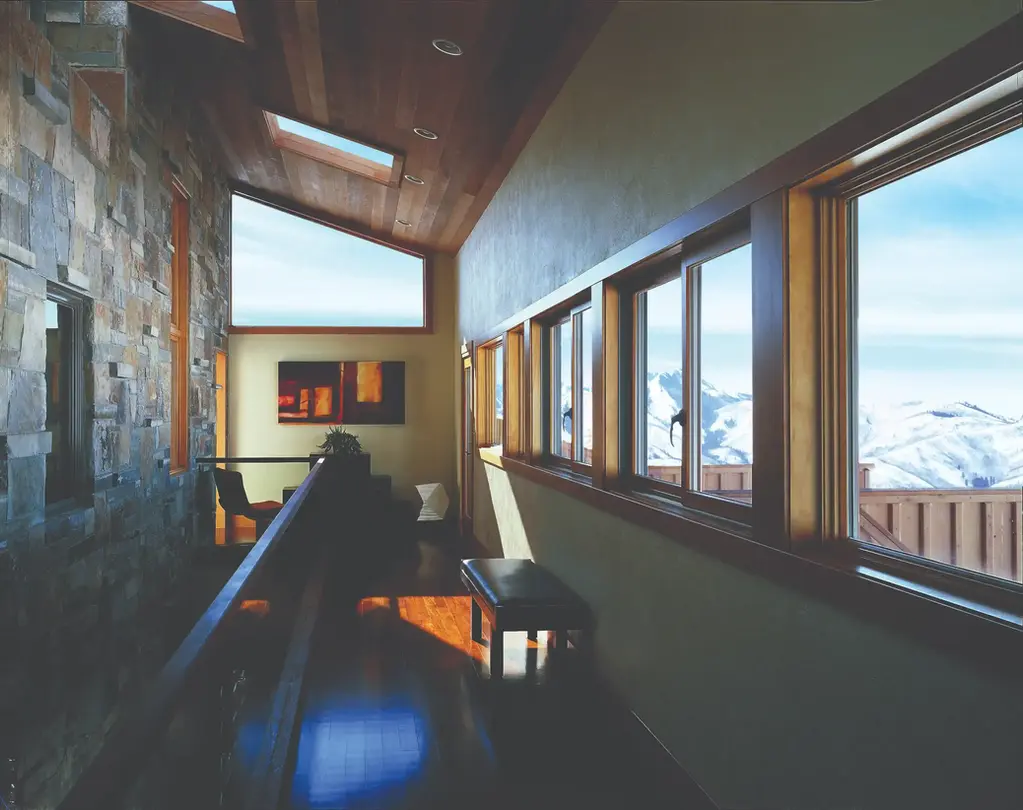 Modern hallway with stone wall, large windows showcasing snowy mountains