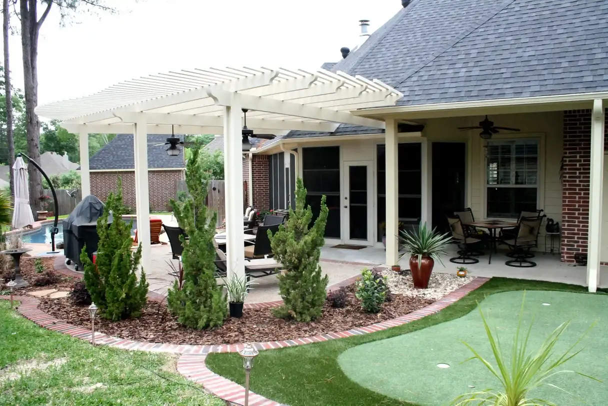 White pergola shading backyard patio with landscaping
