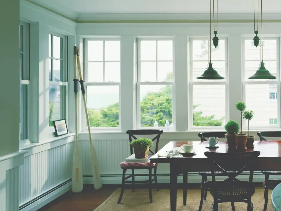 Bright dining room with large windows, wooden table, and hanging lights