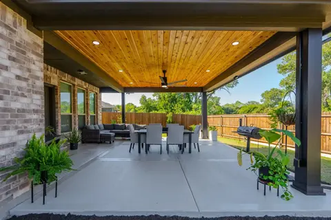 Covered patio with wooden ceiling, seating area, and dining table.