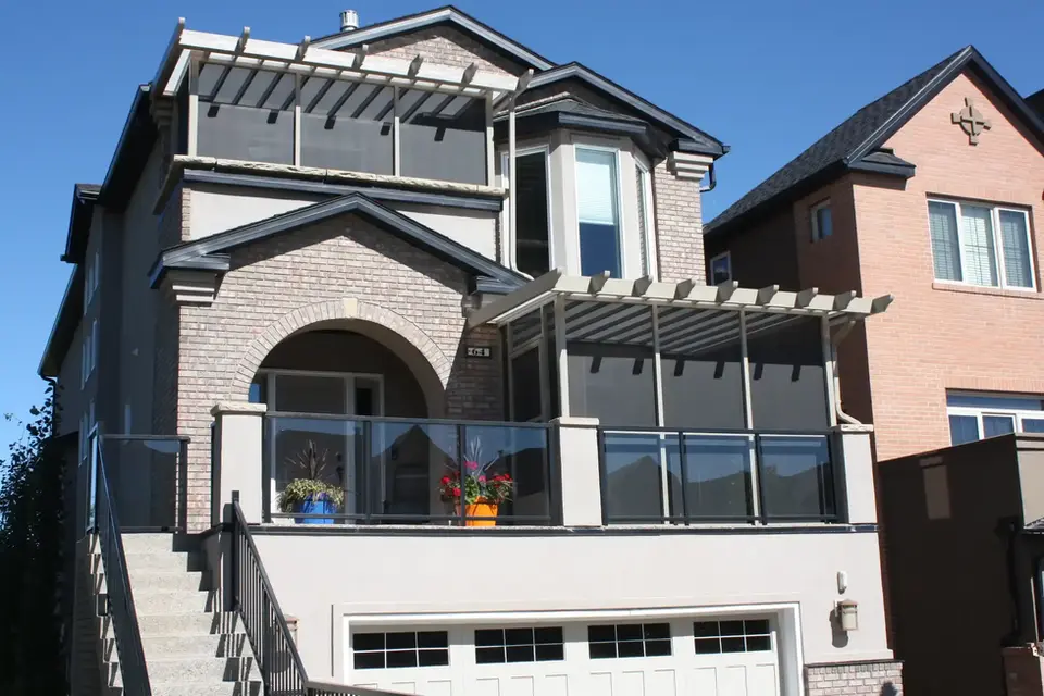 Two-story house with balcony, pergola, and glass railings