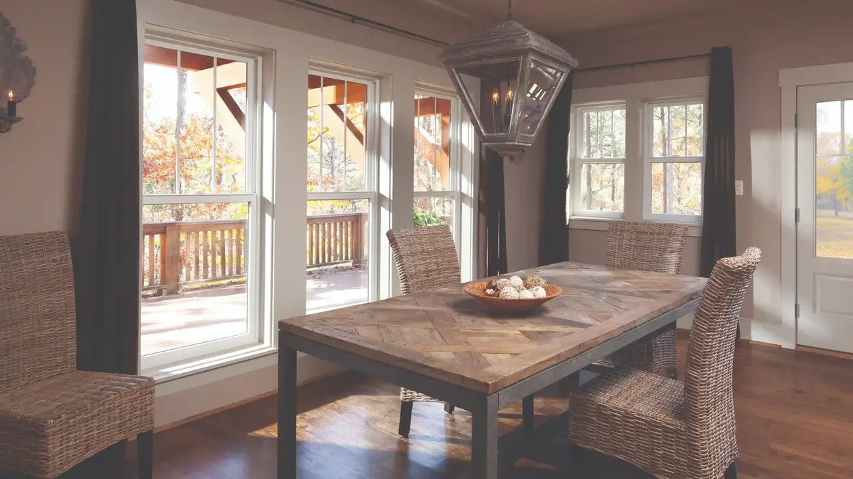 Sunlit dining room with large windows and wooden table