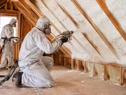 Professionals installing attic spray foam insulation to improve home energy efficiency and comfort.