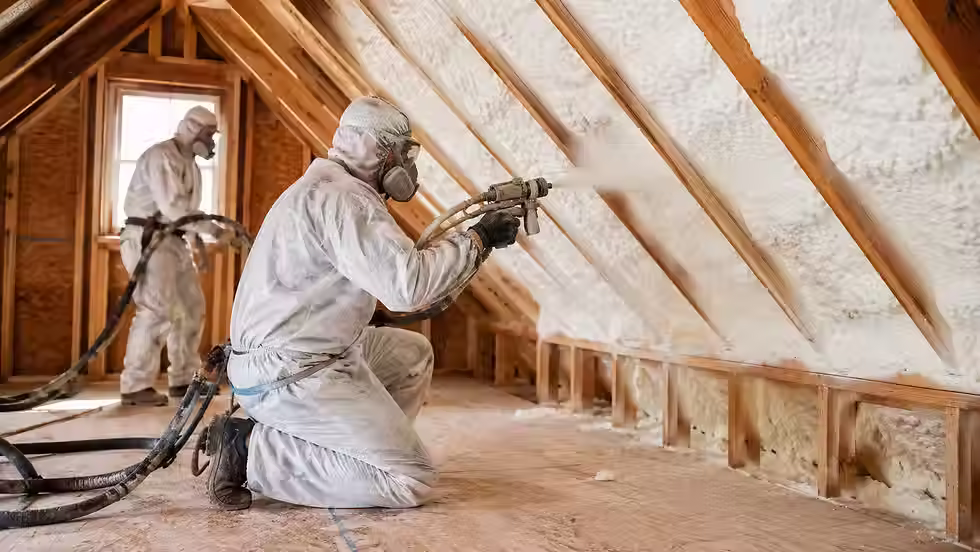 Professionals installing attic spray foam insulation to improve home energy efficiency and comfort.