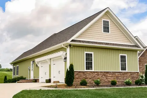 Green two-car garage with white doors and stone accents