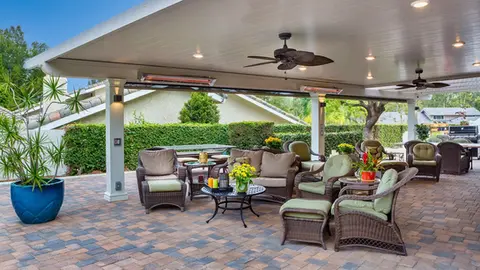 Cozy patio furniture under covered structure with ceiling fan and heaters