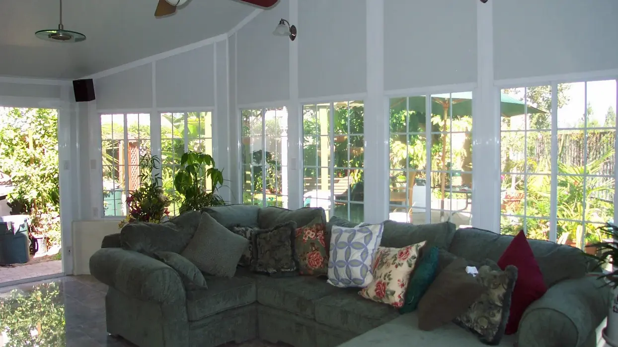 Cozy sunroom addition with sectional sofa and large windows