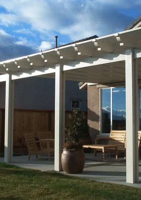 White pergola attached to house, patio furniture underneath