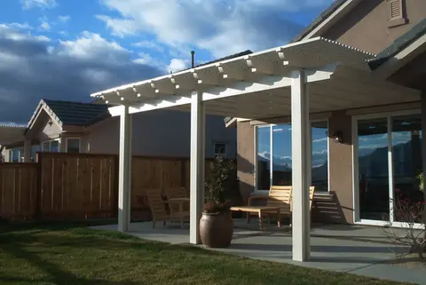 White pergola attached to house, patio furniture underneath
