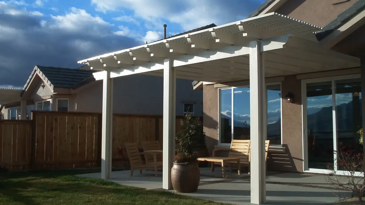 White pergola shading backyard patio furniture