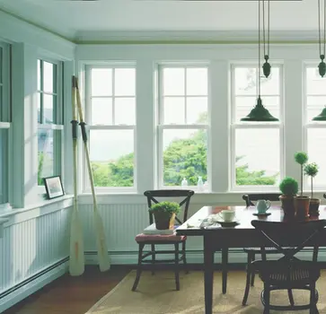 Bright dining room with large windows, wooden table, and oars