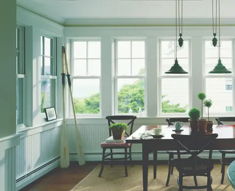 Bright dining room with large windows, wooden table, and oars