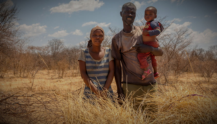 Copy of African family with a child in a village in Botswana standing in front of the bu