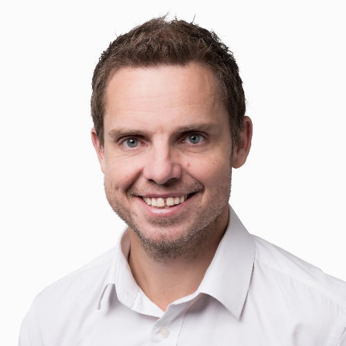 Cameron McKenize smiles in front of a white backdrop.