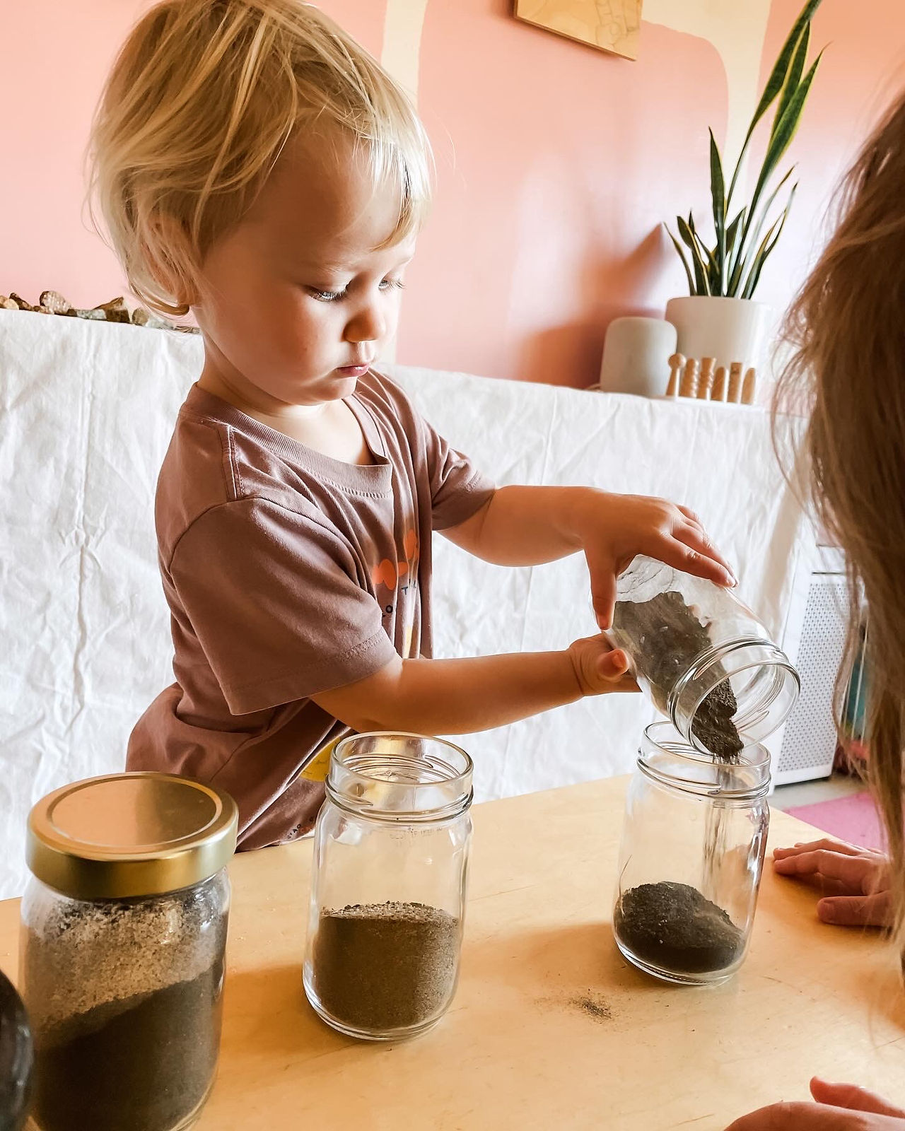 girl pouring soil into jar