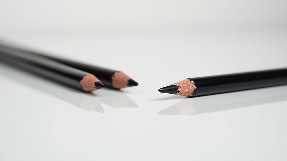 Eye-level view of eyeliner pencils and brushes on a clean white surface