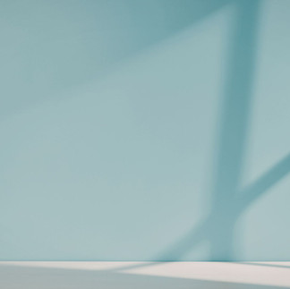 A light blue painted wall demonstrating how strong natural sunlight and shadows affect interior paint colours and finishes