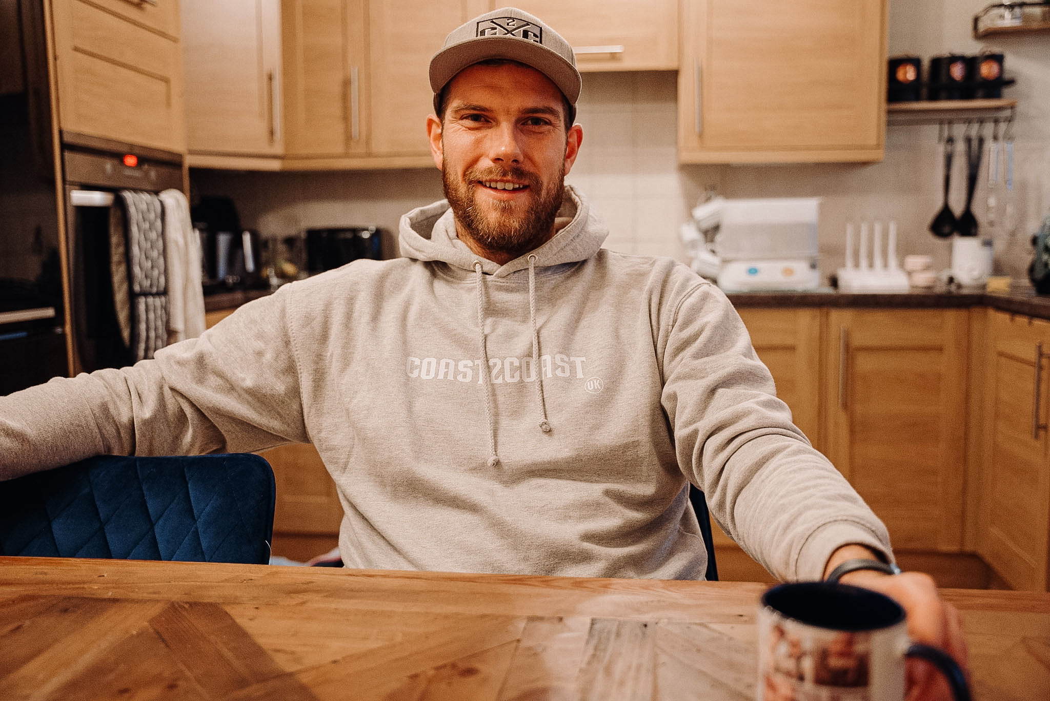 Ben Bowns wearing light grey Hoodie with kangaroo pouch, coast 2 coast logo in white across front chest