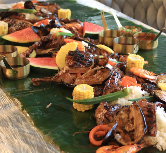 BoodleFight at Dcocina Birmignham. A boodle fight is a communal dining experience where food is served on banana leaves and eaten with hands
Inclusions: Chicken inasal, pork liempo, BBQ skewers, BBQ wings, king prawns, mussels, squid, aubergine, okra, cob corn, ensalada, sauces, watermelon, pineapple, rice and side soup
£24.99 Per head (minimum of 4 people)