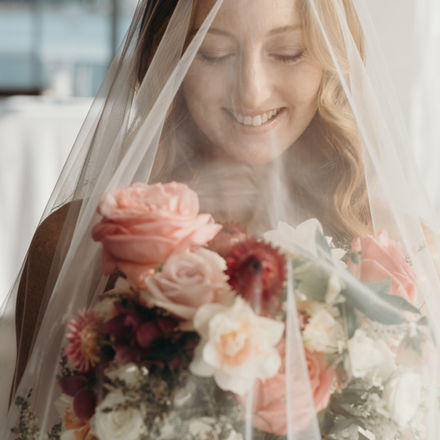 Bride wearing a sheer cathedral bridal veil and holding a pink and white wedding bouquet.