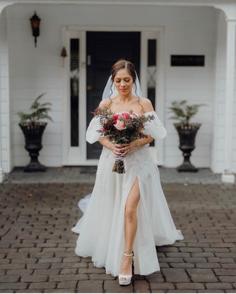 Bride in a bespoke wedding dress walking with a bouquet.