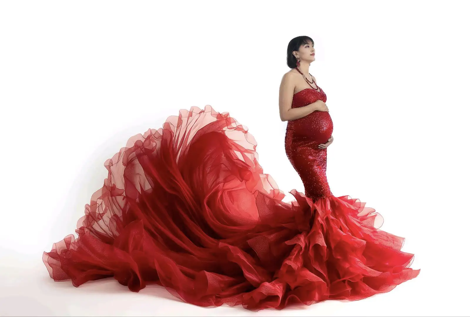 Emotionale Babybauchaufnahme einer werdenden Mutter in einem roten Kleid mit wallendem Stoff – Premium Schwangerschaftsfotos in Düsseldorf