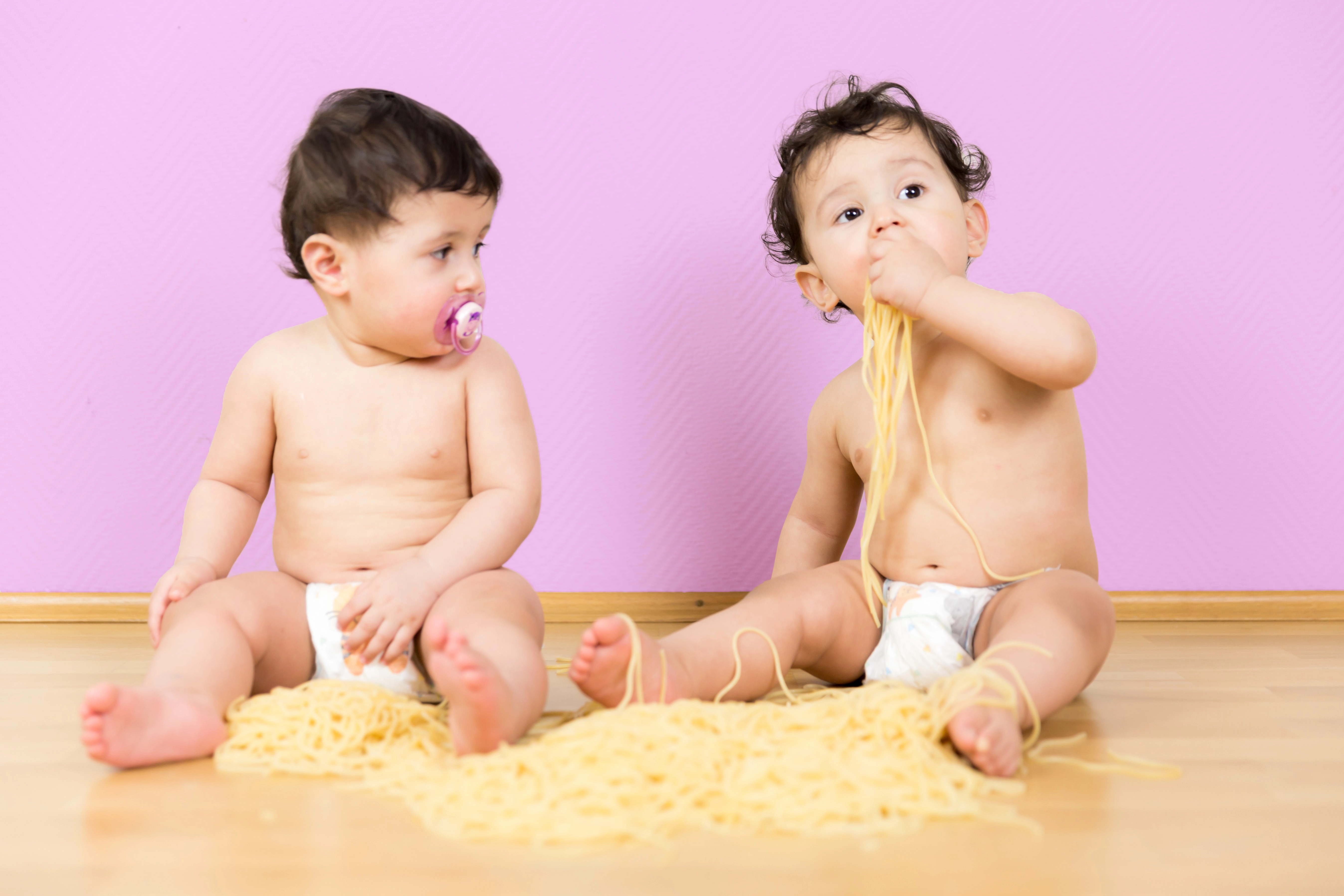 Baby Fotoshooting Düsseldorf – Zwei süße Babys auf weichem Untergrund mit rosa Hintergrund. Professionelle Studioaufnahme für Familien.