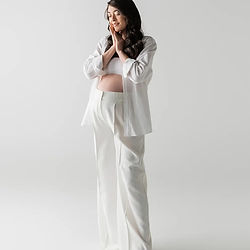 Professionelles Babybauchfoto Düsseldorf – Schwangere steht in weißem Kleid vor hellem Hintergrund
