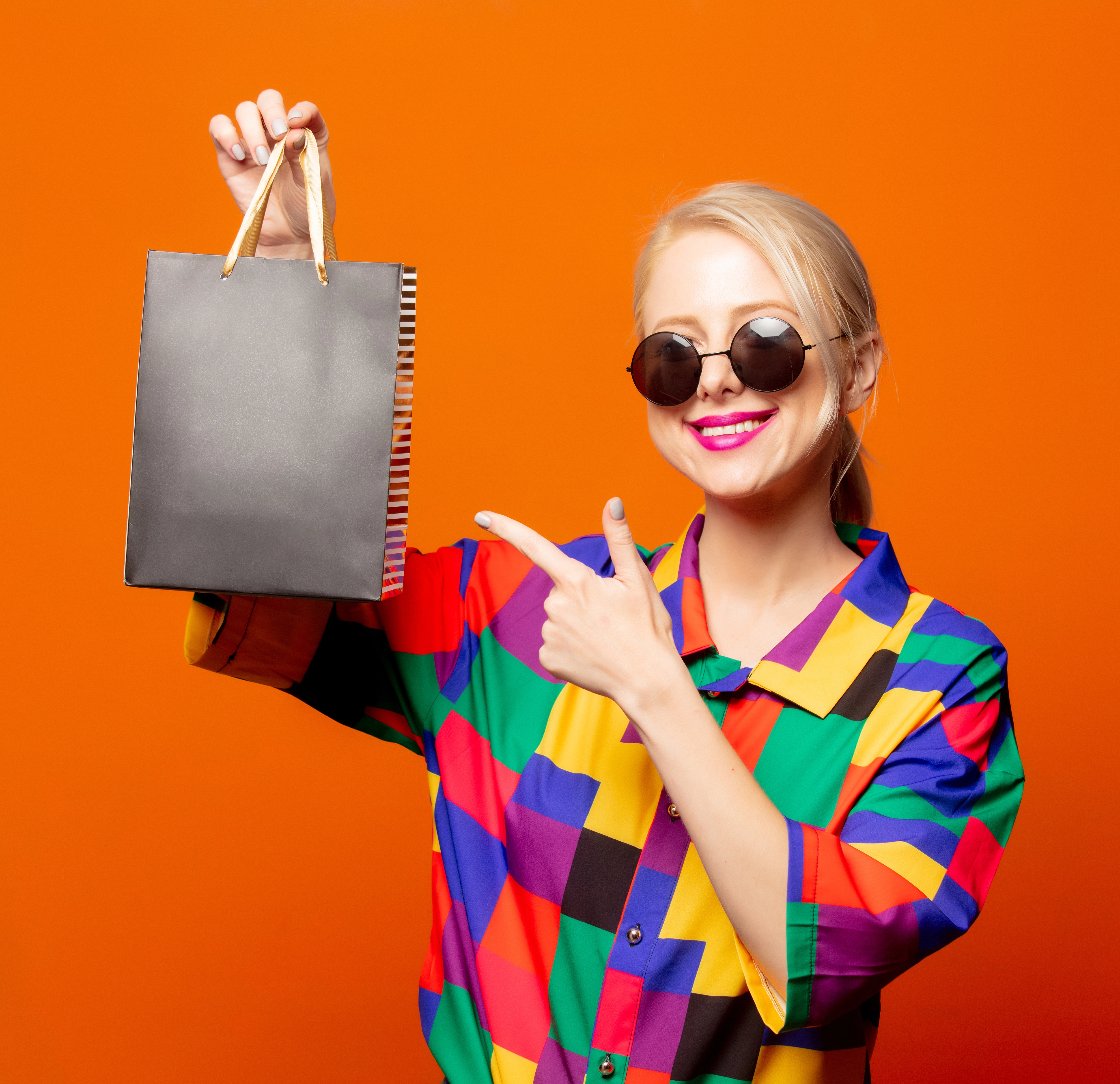 Frau im bunten Outfit mit Sonnenbrille und Einkaufstüte – Studioaufnahme im Diamond Fotoshooting Düsseldorf