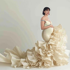 Luxuriöses Babybauch-Fotoshooting – schwangere Frau im eleganten beigefarbenen Kleid mit dramatischem Rock im Studio Düsseldorf