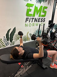 Client performing a dumbbell chest press on a bench during a strength training session