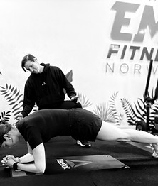 female personal trainer coaching and encouraging a client during a plank exercise