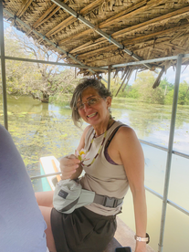 Woman smiles holding a flower on a boat tour in the lake. Friendly Tour Driver.