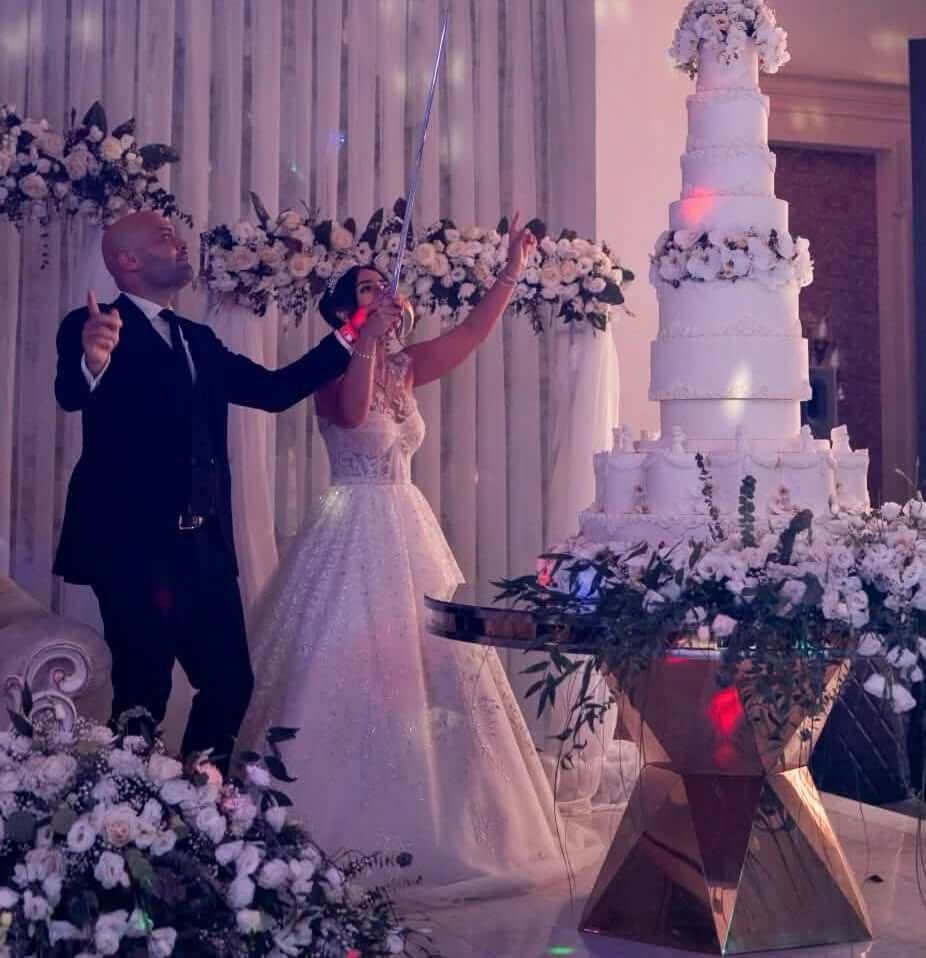 Bride and groom by a wedding cake from Persian catering services.