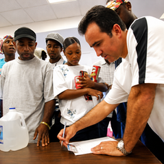 David completing paperwork at a relief distribution site while community members gather around him.