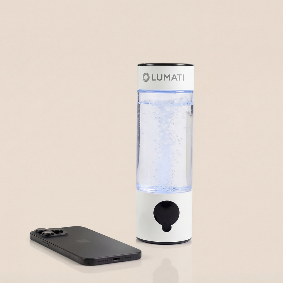 The Lumati Molecular Hydrogen Water Bottle, a tall cylindrical device with a clear chamber containing bubbling water and a white base with a black dial, shown next to a smartphone for scale on a neutral beige surface.