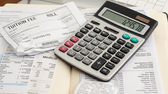 A close-up of a calculator resting on top of a university tuition bill and a folder of medical receipts.