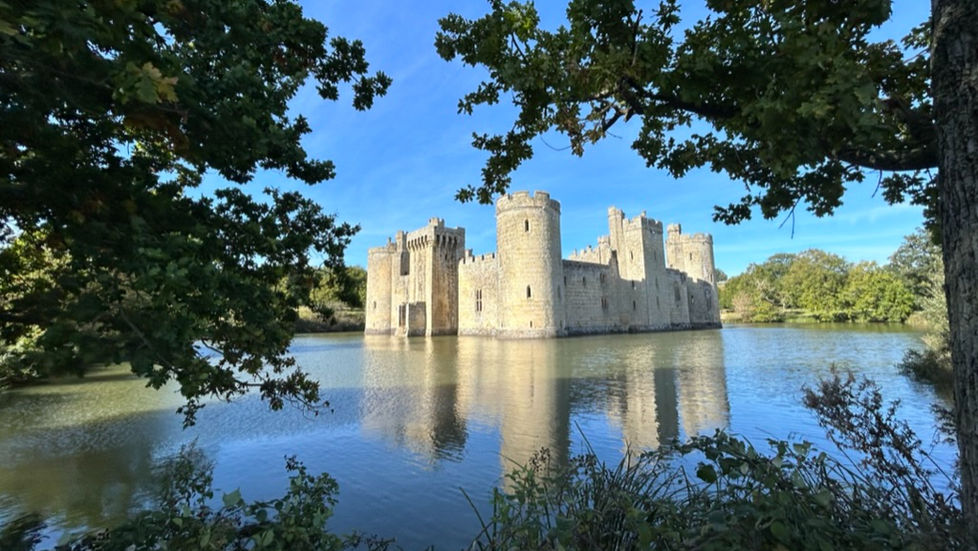 Medieval castle with reflective moat in Autumn sunshine
