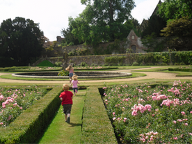 Children running through formal gardens with pink flowers