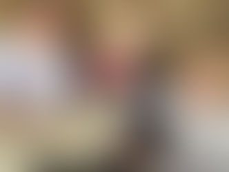 three young children petting a lamb with hay bales behind them