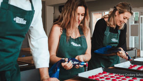 women piping red macrons in green aprons