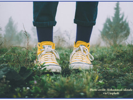 feet with yellow sneakers standing on the ground
