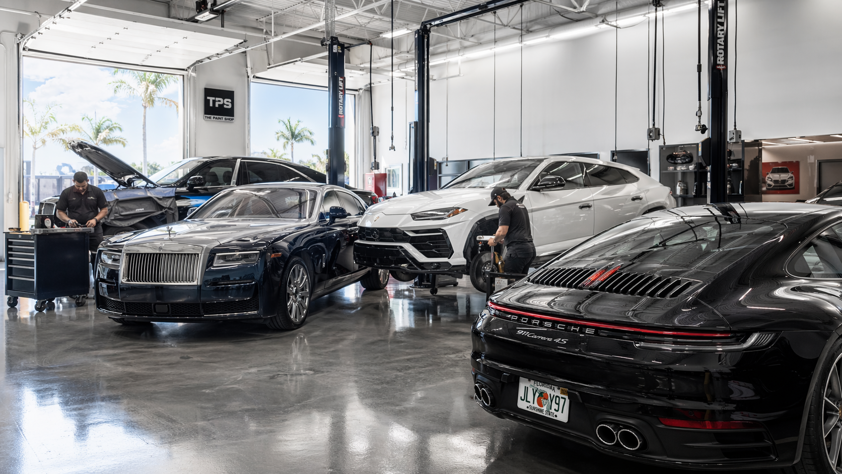 Eye-level view of a modern auto bodyshop with luxury cars being repaired