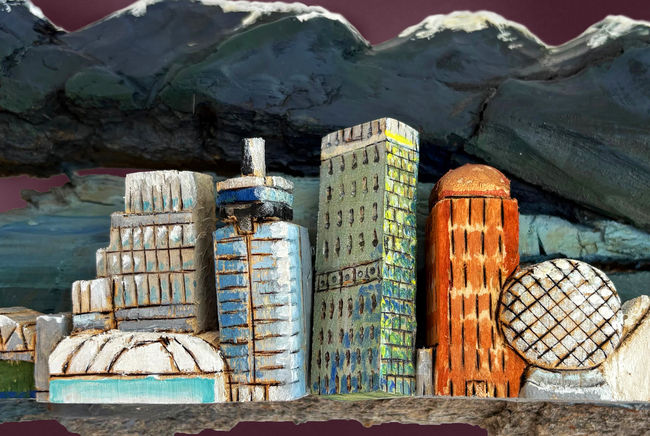 A wood carving depicting the city and mountains of the Vancouver cityscape
